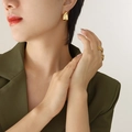 Chic irregular C-shaped gold earrings and chain-textured rings set on female model - Gold