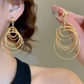 Detailed view of layered gold hoop earrings with sparkling cubic zirconia on a model - Gold Multi-Layer Nested Ring European Exaggerated Tassel Earring / 27# Silver Needle Studs - Gold - Large