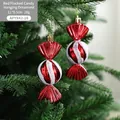 Sparkly red and white candy cane Christmas ornament on a green tree branch - Candy