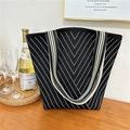 Detailed close-up of knitted tote bag with white V-pattern in a lifestyle cafe setting - 2 Dotted Line Black
