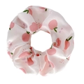 Gros plan du chouchou en soie avec motifs de pêches roses et feuilles vertes - Pomme Blanc
