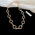 Detailed close-up of golden hollow flower necklace resting on elegant silk fabric background - Necklace - Gold - Flower