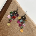 Close-up of Bohemian layered shell fringe earrings with vintage bronze floral metalwork - Colorful