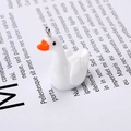 Macro detail of a white resin goose pendant with orange beak and metal loop for DIY jewelry - Goose