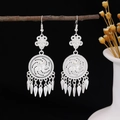 Silver boho hollow flower earrings with leaf tassels hanging on a dry wooden branch - Hollow Pattern Leaf Tassel Style (E5775-21)