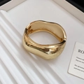 Detailopname van de brede gouden golfarmband met een hooggepolijste spiegelafwerking - Onregelmatige Stijl / Goud