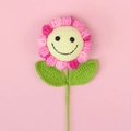 Close-up of pink and yellow hand-knitted sunflower with a cute smiley face on pink background - Gradient Rose Red - Smiling Sunflower Branches