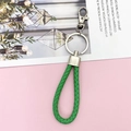 Close-up of bright green braided leather keychain with polished silver metal clasp - Green