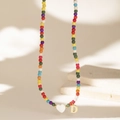 Close-up of a colorful beaded necklace with a white heart charm and a gold letter D pendant - Letter D