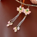 Nahaufnahme der rosa Lotus-Quasten-Ohrringe mit Perlen, die an einem Ast hängen - Ohrhaken-Rosa