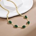 Golden titanium steel snake chain necklace with emerald green oval gemstones on white plate - Emerald Necklace