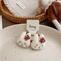 Pair of white plush bunny hair ties with red flower detail on a beige ceramic plate - Red Flower Rabbit Hair Tie