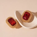 Dettaglio macro di orecchini a perno con rubino rosso e bordo in rilievo dorato - Orecchini a Bottone Rettangolari in Argento con Strass Rossi