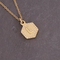 Detailed close-up of golden hexagonal pendant featuring letter L on stone background - Letter L (12#L)