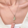 Close-up van een lichtgroene halve maan hanger aan een fijne zilveren ketting - Groen X532