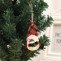 Detail eines hölzernen Wichtels mit Karomuster an einem Weihnachtsbaumzweig - Grüne Socke Stil