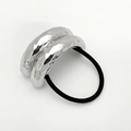 Nahaufnahme eines silbernen gewellten Metallaccessoires an einem schwarzen Haargummi - Silber