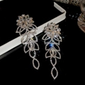 Orecchini a fiori argentati con nappine e diamanti su una superficie scura riflettente - Argento