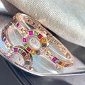 Gros plan d'une montre bracelet en or rose avec zircons colorés et cadran blanc - Or rose
