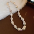 Detail of baroque pearl necklace with iridescent luster on brown and white plush surface - White (Large)