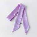 Detail eines lila Satin-Twilly-Schals mit silbernen Perlenverzierungen und seidiger Textur - Helllila