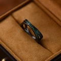 Close-up of a black crisscross ring featuring inlaid green cubic zirconia on velvet box - US Size 6 / Gun Black - Green Zirconia