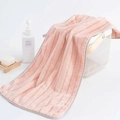 Pink coral fleece towel with grey trim and stripes in a white decorative basket - Pink