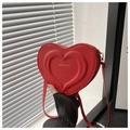 Close-up of red heart-shaped PU leather crossbody bag with FASHION & BAG text engraving - Red