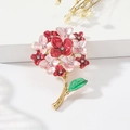 Dettaglio della spilla a fiore in smalto colorato con strass e ramo di foglia d'oro - Rosso + Rosa
