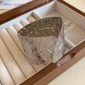 Macro shot of silver wide metal bangle with leaf texture and hinge detail in a gift box - Silver Wide Leaf Pattern Hinge Closure Style