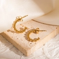 Detail of gold beaded C-shape hoop earrings on textured stone and white silk background - Open C-Shape Metal Bead Earrings