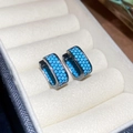 Close-up of turquoise stones encrusted on black gold hoop earrings in a jewelry box - Lake Blue