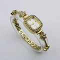Detail view of gold square bracelet watch with rhinestone flower band and white dial - Gold Case White Dial