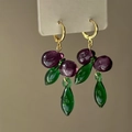 Close-up detail of gold-plated grape earrings with purple glass beads and green leaves - Hoop Buckle Style / Gold Purple Green Combination