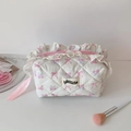 Nahaufnahme der gesteppten Kosmetiktasche mit Blumenmuster, Schleife und Spitzenbesatz - Weiß