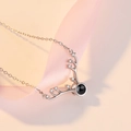 Macro shot of silver deer antler necklace with crystals and 100 languages projection stone - Diamond Row Antler White Gold Color
