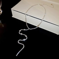 Macro dettaglio di una collana a Y argentata con strass lucidi su una scatola di gioielli - Argento