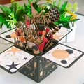 3D-Pop-up-Geburtstagskarte in Schwarz und Gold mit glitzernden Party-Elementen und Sternen - Schwarz