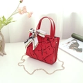 Detail of red marble print handbag featuring a silk scarf bow and gold chain strap - Red