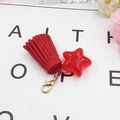 Close-up of a red star pendant with suede tassel and metal lobster clasp detail - Red