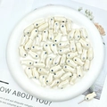 Macro shot of white ceramic fish beads with blue eyes and pearl luster for jewelry DIY - Off-white