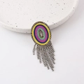 Macro detail of bohemian colorful beaded brooch with sparkling rhinestone tassels - Letter O