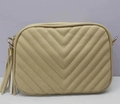 Dettaglio della borsa fotografica trapuntata beige con cuciture a V e nappa decorativa - Albicocca