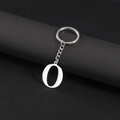 Polished stainless steel letter O keychain pendant on black leather background - Letter O