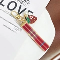 Detalle del llavero de fresa con cinta de cuadros rojos y accesorios de metal dorado - Fresa de Cuadros