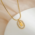 Macro view of gold snake chain with zircon oval frame and engraved letter X pendant - Letter X