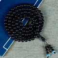 Bracciale mala in sandalo rosso con accenti turchesi posato su un libro d'epoca - Stella d'Oro Nero Rosso 8mm*108 Perle (Zucca + Turchese)