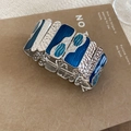Dettaglio macro del bracciale elastico con tessere in smalto blu e texture martellata argento - Argento-Blu