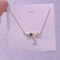 Dettaglio ravvicinato del ciondolo a stella e pianeta dorato con perla e pietra blu - Pianeta Perla Strass (XK0047)