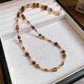 Detail of 18K gold plated tiger eye beaded necklace on beige velvet display case - Vintage Beaded Style / Gold Brown